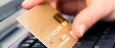 Closeup of a hand holding a credit card over a computer keyboard